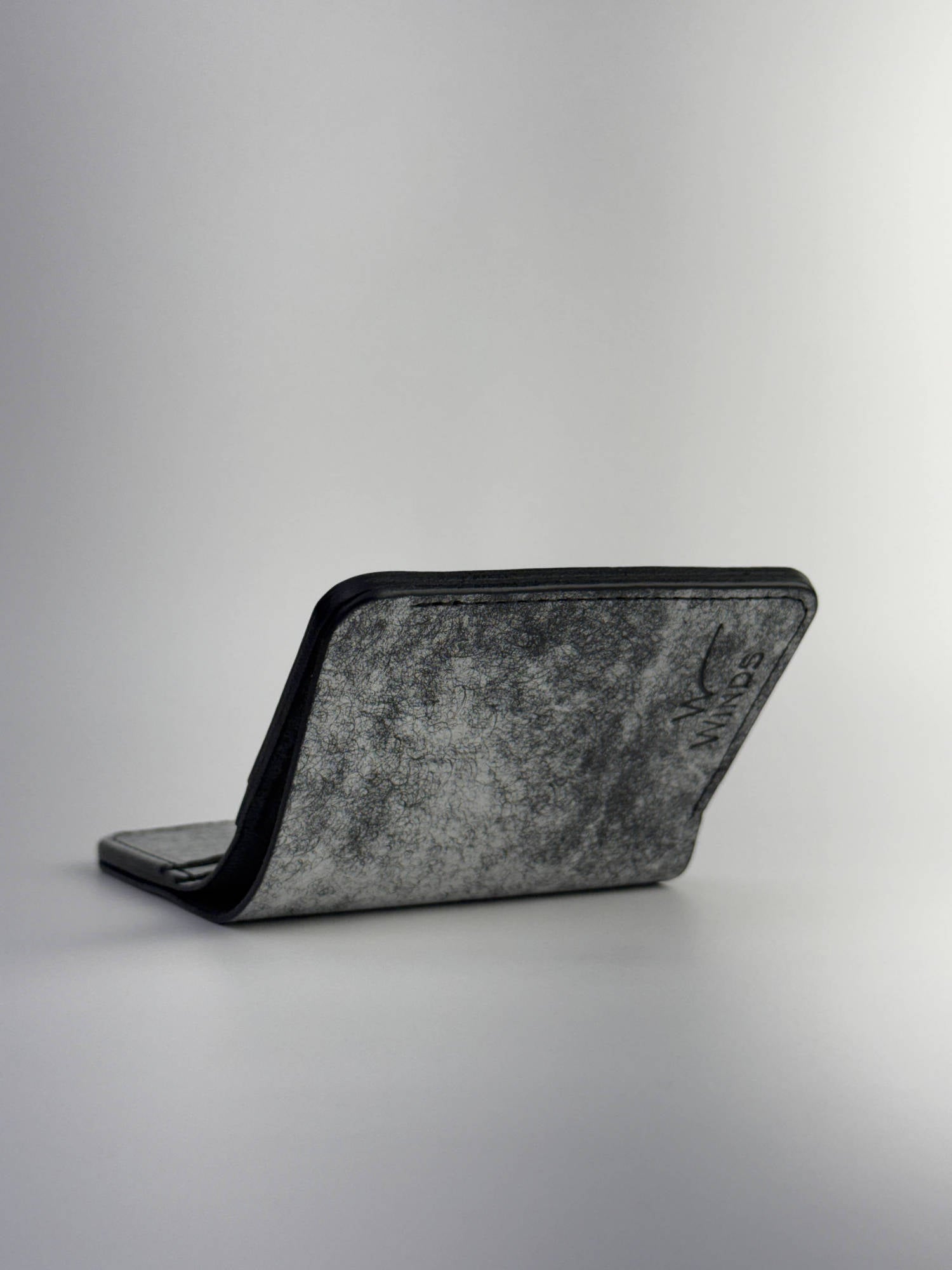 black glance leather wallet lying opened front view with Winds logo, on a white background