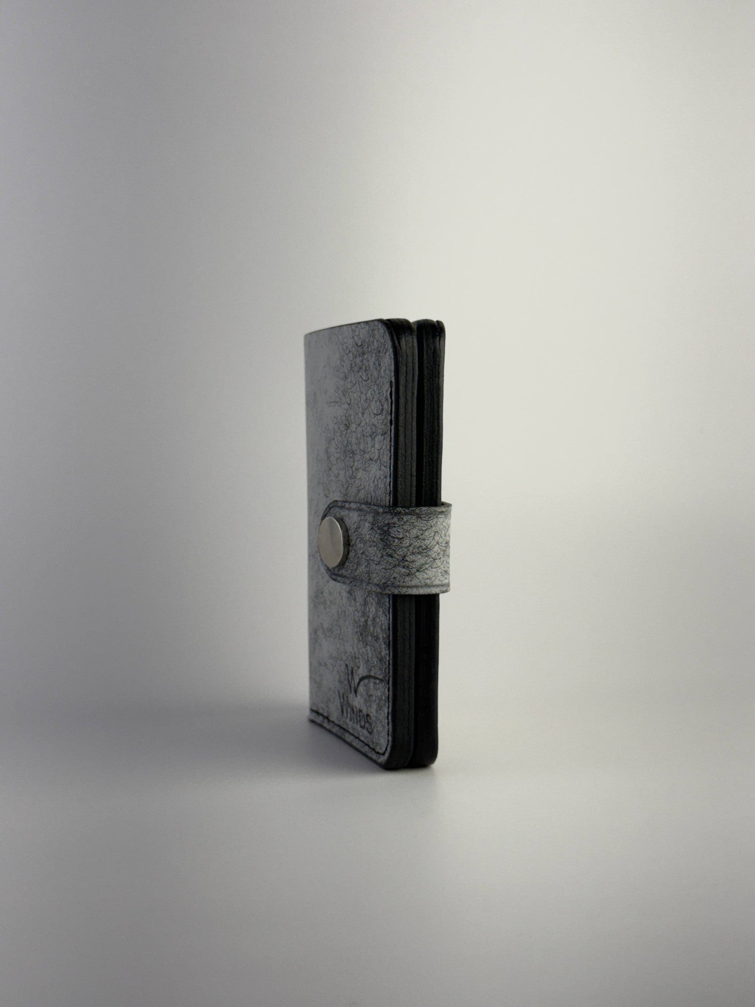 black glance leather wallet with button closure edge side view on white background