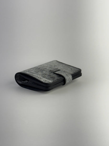 black glance leather wallet with button closure lying closed back side view on white background