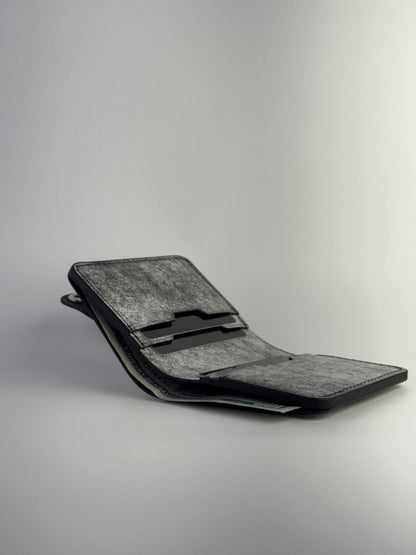 black glance leather wallet with button closure lying opened with cards and cash side view on white background