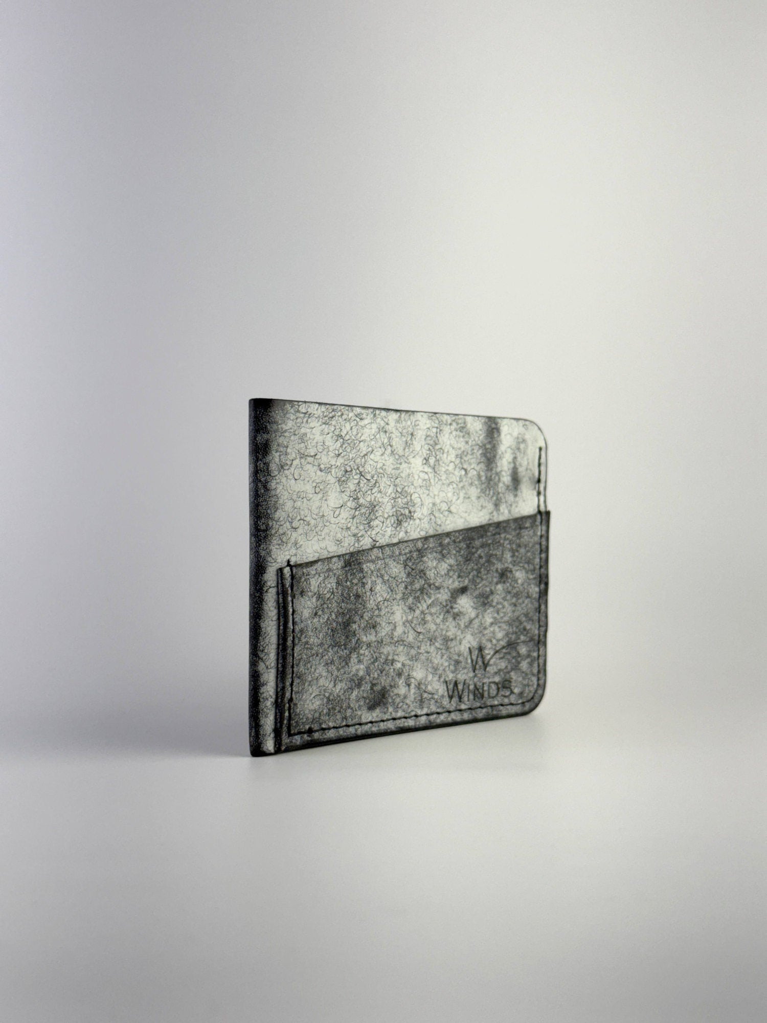 black wing leather cardholder rotated front side with Winds logo, on a white background
