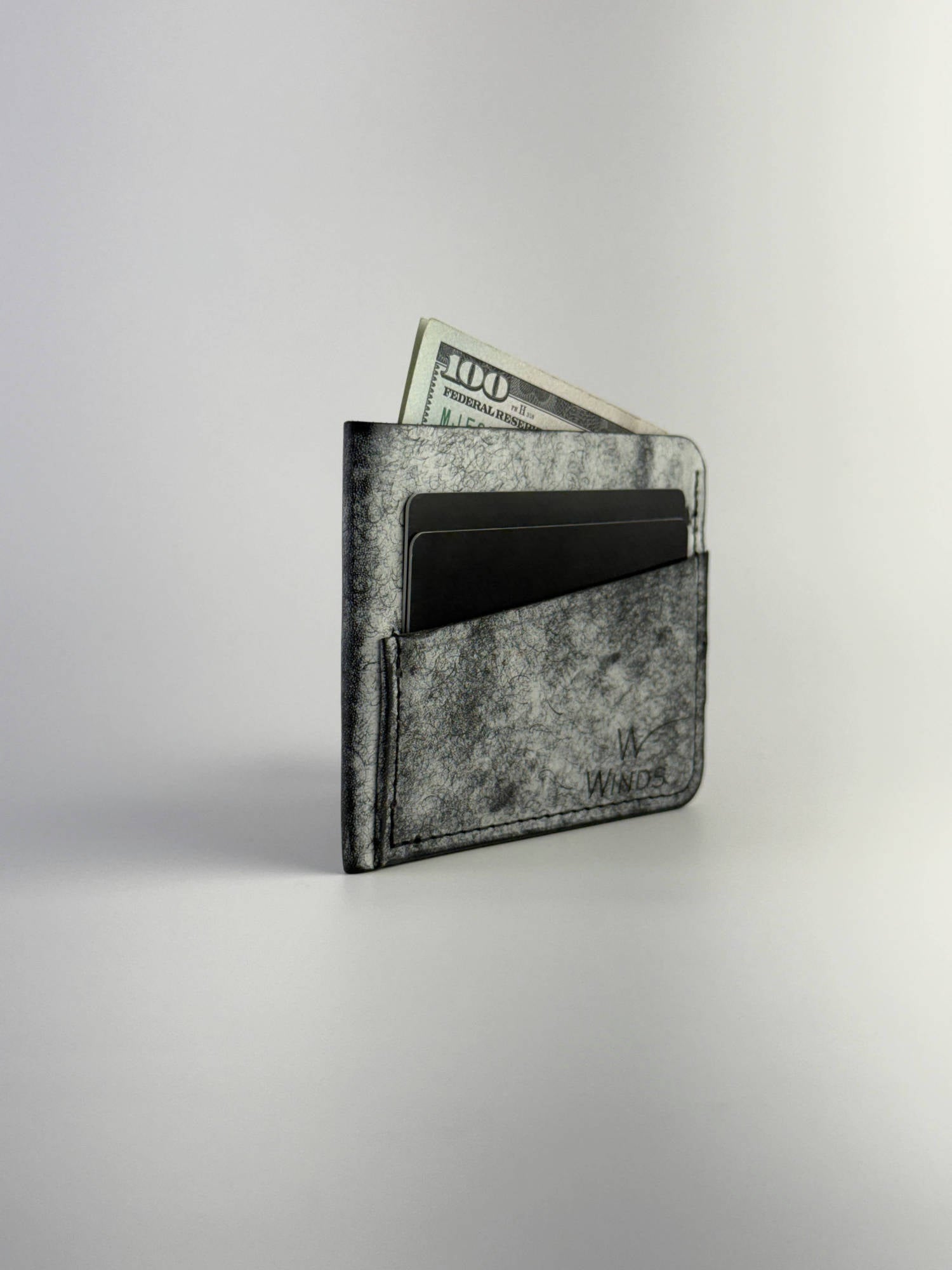 black wing leather cardholder rotated front side with cards, cash and Winds logo, on a white background