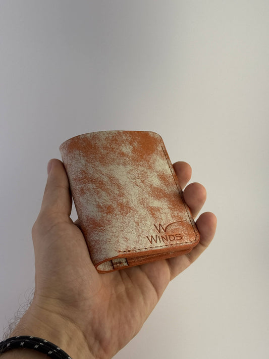 orange glance leather wallet front side view with hand and Winds logo, on a white background